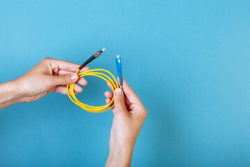 Wall Mural - woman's hands hold SC and FC connector fiber optic patch cord single mode on blue background