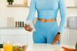 Leinwandbild Motiv Female fitness blogger using smartphone in the kitchen, black lady in sportswear preparing healthy dinner at home