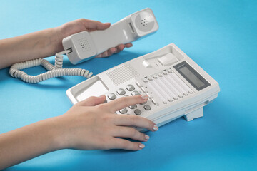 A woman calls on a landline wired phone.