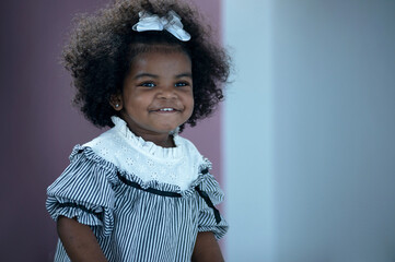 Cute African little girl wearing a white bow, smiling happy young African American girl