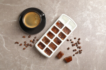 Ice cubes, cup of coffee and beans on grey table, flat lay