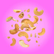 Leinwandbild Motiv Tasty cashew nuts flying on pink background