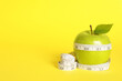 Leinwandbild Motiv Fresh green apple with measuring tape on yellow background. Space for text