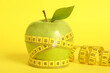 Leinwandbild Motiv Fresh green apple with measuring tape on yellow background, closeup