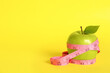 Leinwandbild Motiv Fresh green apple with measuring tape on yellow background. Space for text