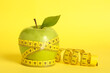 Leinwandbild Motiv Fresh green apple with measuring tape on yellow background