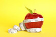 Leinwandbild Motiv Fresh red apple with measuring tape on yellow background
