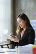 © kamiphotos - A beautiful Asian businesswoman sitting in her private office, she is checking company financial documents, she is a female executive of a startup company. Concept of financial management.