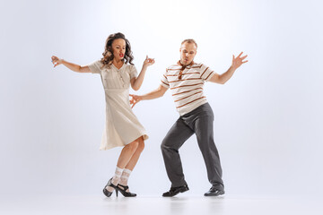 Excited young man and woman in retro style outfits dancing lindy hop isolated on white background. Timeless traditions, 60s ,70s american fashion style.