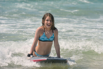 Cute portrait of a girl bodyboarding in the waves in summer