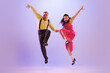 © master1305 - Active and emotional couple in colorful retro style costumes dancing incendiary dances isolated on purple background in neon light. Concept of art, culture