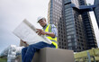 © Basicdog - African male civil engineer inspects a commercial building construction site in a real estate project.