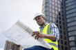 African male civil engineer inspects a commercial building construction site in a real estate project.