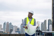 © Basicdog - African male civil engineer inspects a commercial building construction site in a real estate project.
