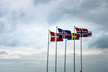 Scandinavian Flags Fluttering In The Sky Reminds Of The Historical Kalmar Union Between Sweden, Denmark, Iceland, Faroe Islands, Greenland And Norway Against The Hanseatic League Economical Influence