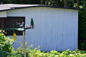 A view of a homemade figurine including two dwarves, a christmas tree and a saw made out of wood located in front of an old abandoned shack or shelter spotted in Poland on a sunny summer day 