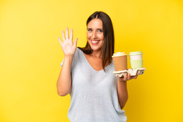 hispanic young adult woman smiling happily, waving hand, welcoming and greeting you. take away coffee concept