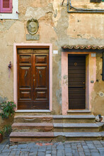 Façade Of An Old Building With Wooden Doors At The Top Of Steps, Tuscany, Italy