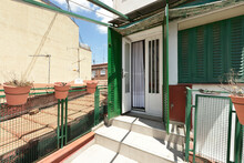 Attic Terrace With Green Metal Latticework, Clay Pots And Views Of The Rooftops, White Aluminum Access Door With Green Security Bars And Other Dwellings