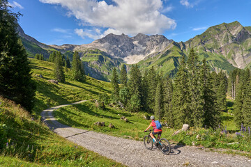 Wall Mural - active senior woman, riding her electric mountain bike in the Arlberg mountain range near the famous village of Lech, Tirol, Austrian Alps