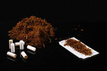 Wall Mural - Filters and paper on a background of rolling tobacco on a dark table with reflection. Shallow depth of field