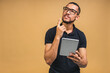 © denis_vermenko - Working on digital tablet. Portrait of happy smiling young African american black man holding digital tablet while standing isolated over beige background.