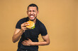 © denis_vermenko - Hungry young african american black man eating hamburger isolated over green background. Stomach ache.