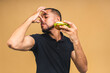 © denis_vermenko - Stop sign, bad smell. Young african american black man eating hamburger isolated over beige background. Diet concept.
