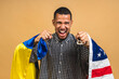 © denis_vermenko - Portrait of positive african american black guy holding usa and ukrainian flags, isolated over beige background.