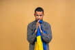 © denis_vermenko - Portrait of sad negative african american black guy holding ukrainian flag, isolated over beige background.