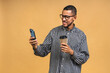 © denis_vermenko - Portrait of handsome excited thinking serious african american black guy wearing casual sending and getting messages to his lover isolated over beige background. Using phone.