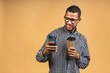 © denis_vermenko - Portrait of handsome excited thinking serious african american black guy wearing casual sending and getting messages to his lover isolated over beige background. Using phone.