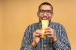 © denis_vermenko - Hungry young african american black man eating sandwich isolated over beige background. Diet or Fast food concept.