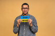 © denis_vermenko - Stop war! Save Ukraine! Portrait of sad negative african american black guy holding ukrainian flag, isolated over beige background.