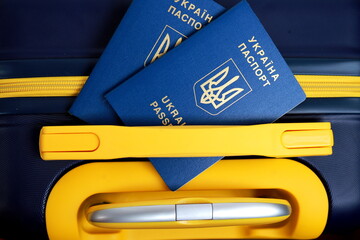 2 passports of citizens of Ukraine lie on yellow blue suitcase in color of Ukrainian flag at border. Travel concept, refugees, tourism