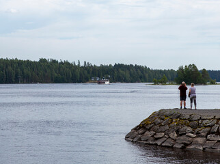 Wall Mural - Elderly caucasian couple taking pictures of a big ship on the lake.