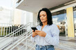 © kleberpicui - Businesswoman using smartphone in the city.