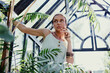Beautiful sexy woman picking flowers in the greenhouse. Florist at work. The farmer grows plants. Peasant woman in the village. Romantic retro image of girl. Confidence sexuality portrait. Atmosphere