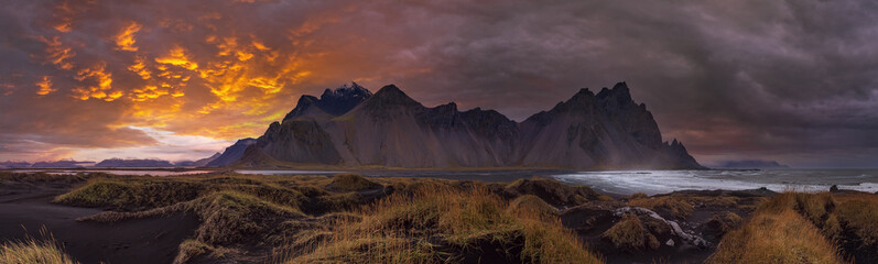 Wall Mural - Pre sunrise Stokksnes cape sea beach and Vestrahorn Mountain, Iceland. Amazing nature scenery, popular travel destination. Autumn grass on black volcanic sand dunes.