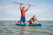 © spass - Happy teenage siblings having fun on paddle board at sunny summer day at vacation on sea
