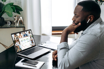 Wall Mural - Online business meeting, briefing. African american successful entrepreneur, ceo, sitting at a desk, having a financial brainstorm with colleagues on a video conference, analyzing a financial strategy