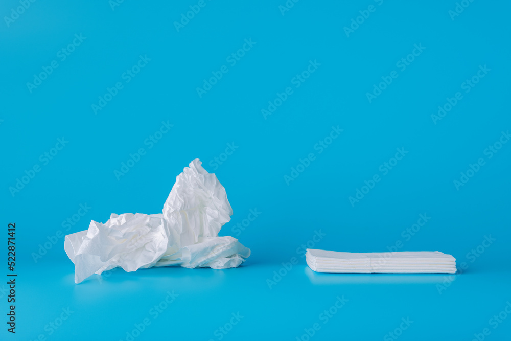 On a blue background, a used crumpled paper handkerchief and new clean ...