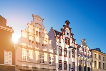 Old historic buildings in Wismar, Germany. Empty square early morning. Sunny day with blue sky, sun flare.