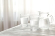 Jug and glasses of water on white wooden table
