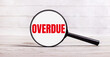 The magnifying glass stands vertically on a light background with the text OVERDUE