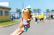 Melted ice cream from the hot summer weather in a woman hand on the background of a city street