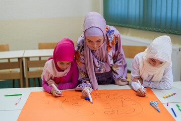 Group of happy Muslim school children with their teacher working on project together at classroom.	