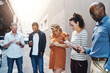 © Tamani Chithambo/peopleimages.com - Business people reading text on phone, checking notifications and typing messages online during a break at work. Group of diverse colleagues scrolling on the internet, browsing app and networking