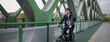 Businessman commuter on the way to work, riding bike over bridge, sustainable lifestyle concept. Wide shot.