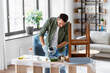 © Syda Productions - repair, diy and home improvement concept - man in protective gloves pouring grey color paint to tray for painting old wooden table